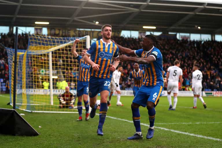 Shrewsbury player takes corner while reading note, and delivers perfect cross to his teammate to score