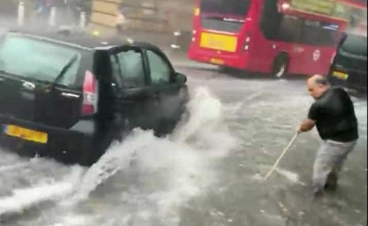 Man filmed using a broom to try clear shin-deep water during London floods