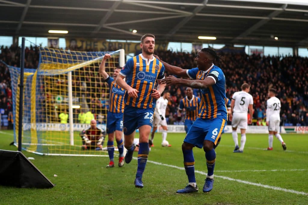 Shrewsbury player takes corner while reading note, and delivers perfect cross to his teammate to score