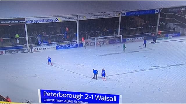 Peterborough player sweeps through snow to make pitch lines visible so match can finish Peterborough player sweeps through snow to make pitch lines visible so match can finish