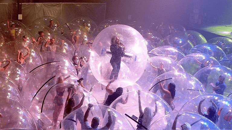 Fans in plastic bubbles watched The Flaming Lips perform, also in plastic bubbles Fans in plastic bubbles watched The Flaming Lips perform, also in plastic bubbles