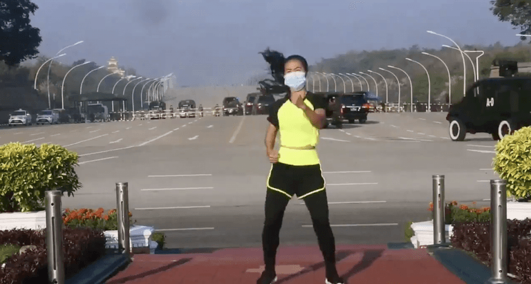 Exercise instructor does aerobics class while military coup takes place behind her Exercise instructor does aerobics class while military coup takes place behind her