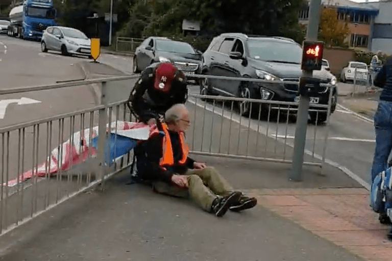 Insulate Britain protestor tied to railing with own banner by angry driver Insulate Britain protestor tied to railing with own banner by angry driver