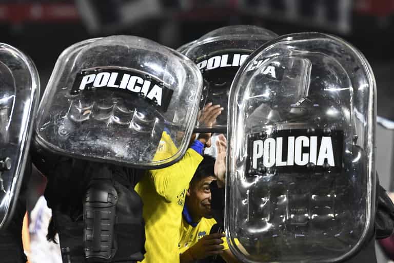 Boca Juniors players helped off pitch by riot police after Superclásico win Boca Juniors players helped off pitch by riot police after Superclásico win
