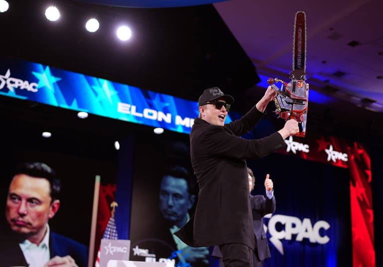 Elon Musk wields chainsaw and dances on stage in bizarre appearance Elon Musk wields chainsaw and dances on stage in bizarre appearance