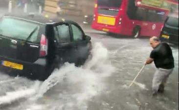 Man filmed using a broom to try clear shin-deep water during London floods